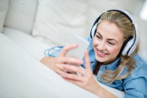 Woman listening to music at home on her cell phone and using headphones